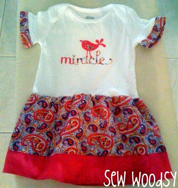White onesie with the word "miracle" on the shirt with a paisley skirt.
