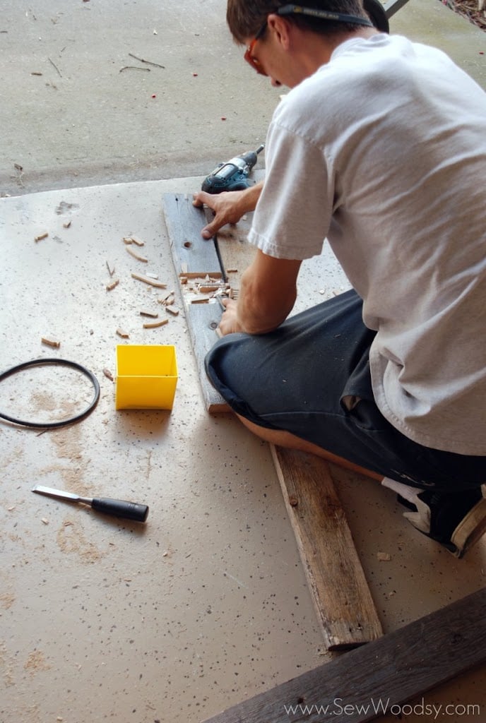 Man chiseling wood to make a slat to cross over.