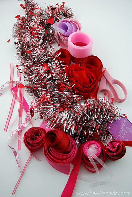 Supplies on table; garland, red, pink, and purple ribbon scraps and scissors.