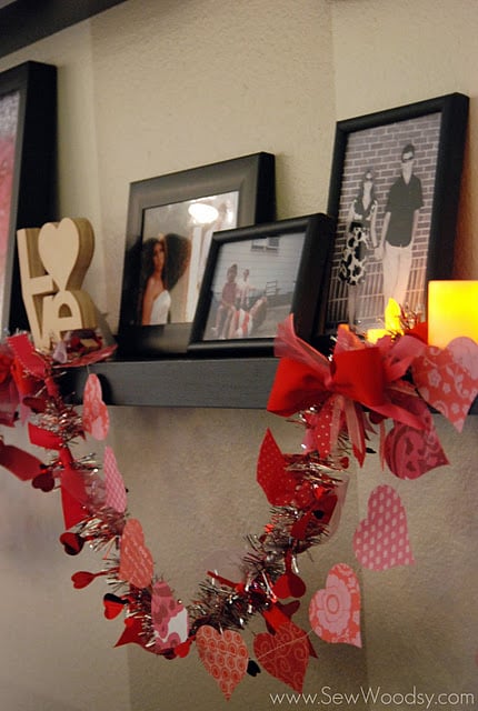 Black shelf with garland and paper hearts hanging from it.