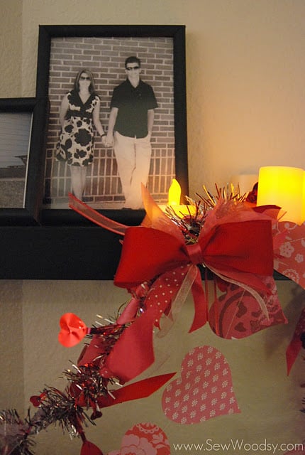 Close up of ribbon and bow garland on a black shelf with picture frame of husband and wife.