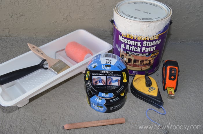 supplies on patio; chalk reel, measuring tape, pencil, painting tray, paint, painters tape.