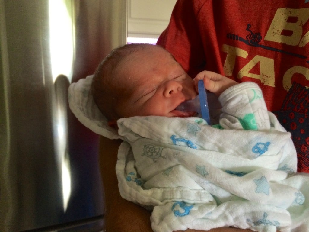 newborn holding his paci.