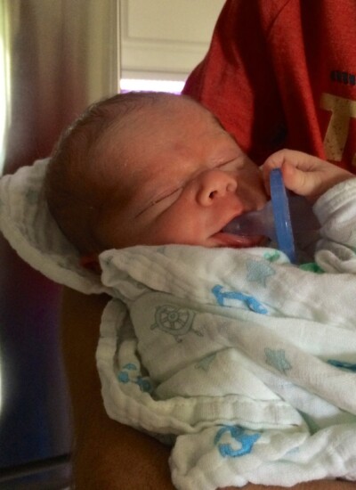 newborn holding his paci.