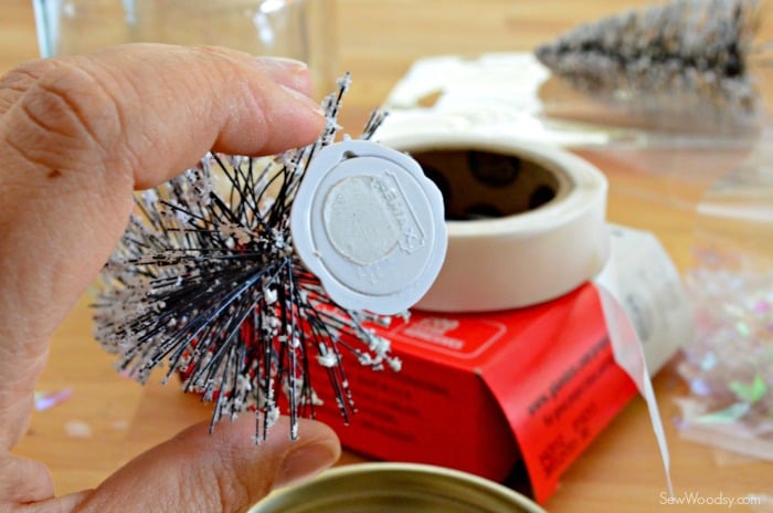 Female hand holding a wire bottle brush tree with a glue dot on the bottom.