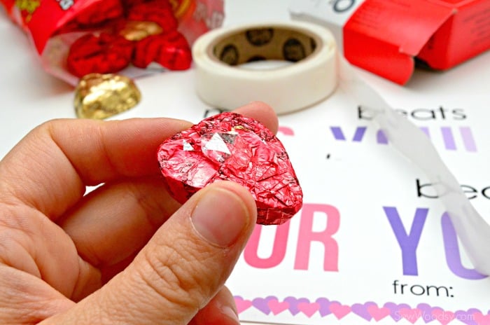 Hand holding a reese's heart with sticker on it.