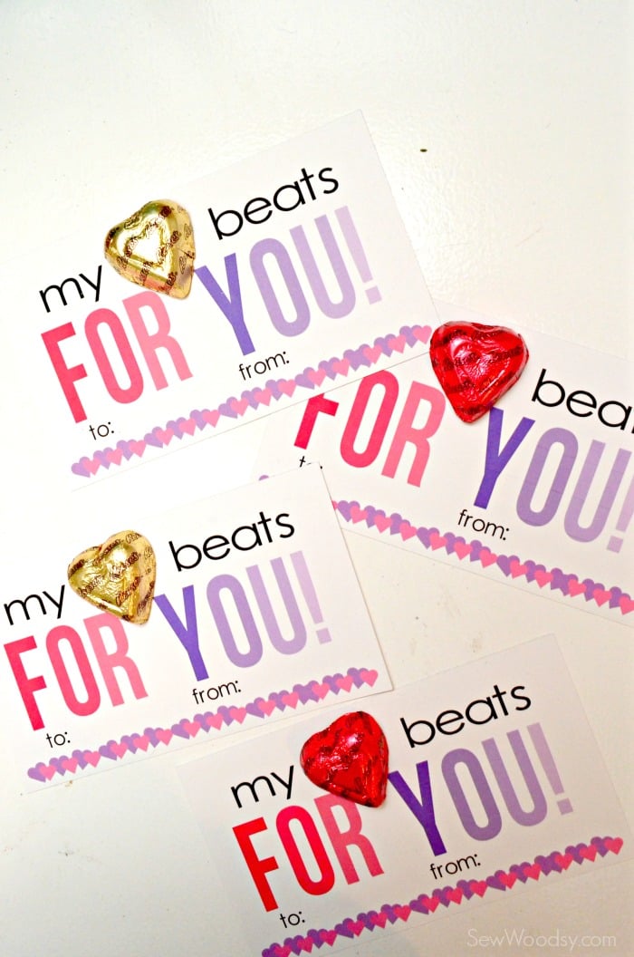 Four Valentine cards on a white desk with candies on top.