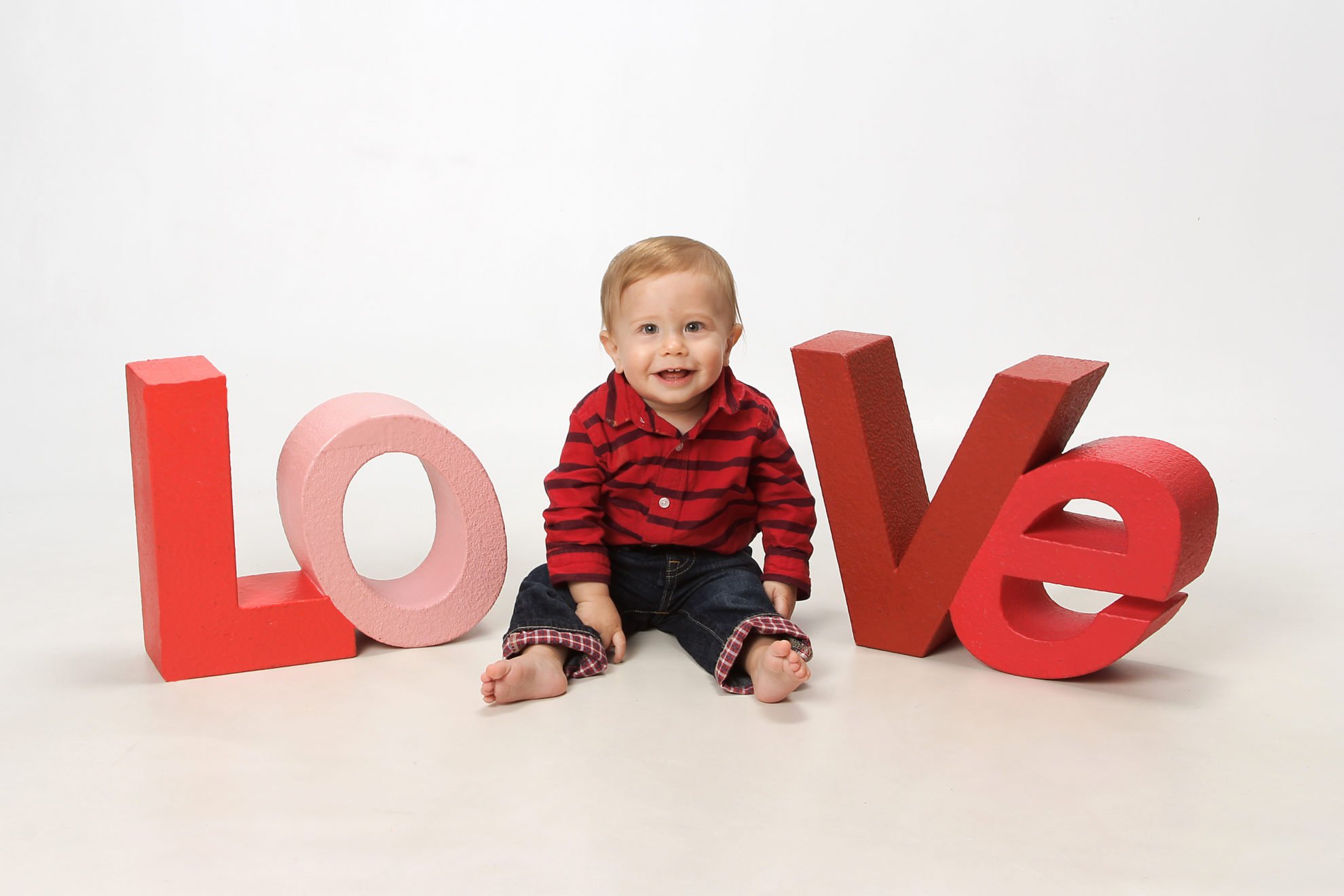 The letters "l o v e" with a baby sitting in the middle.