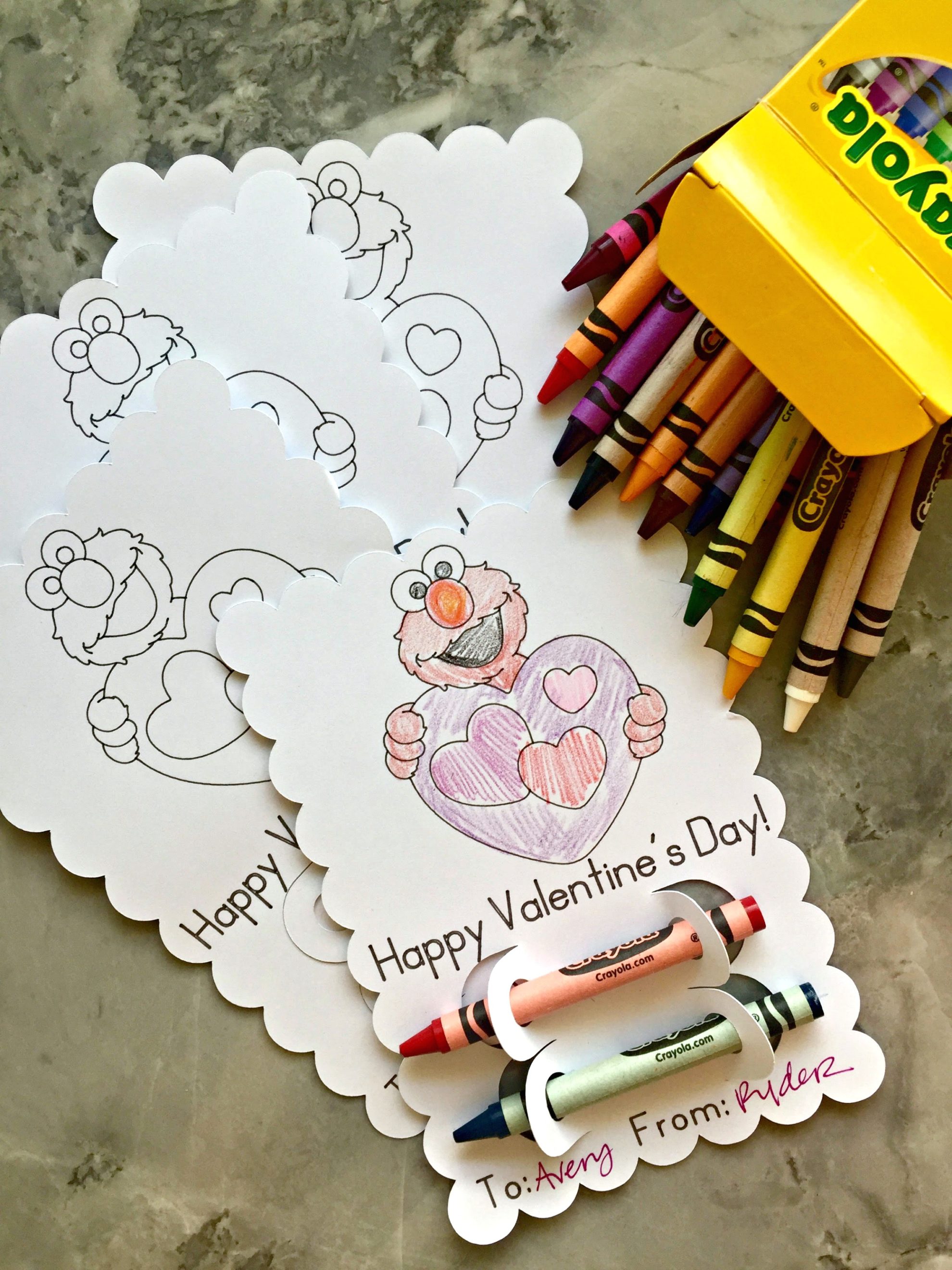Top view of multiple scalloped edge Elmo coloring valentine's with crayons on the counter.