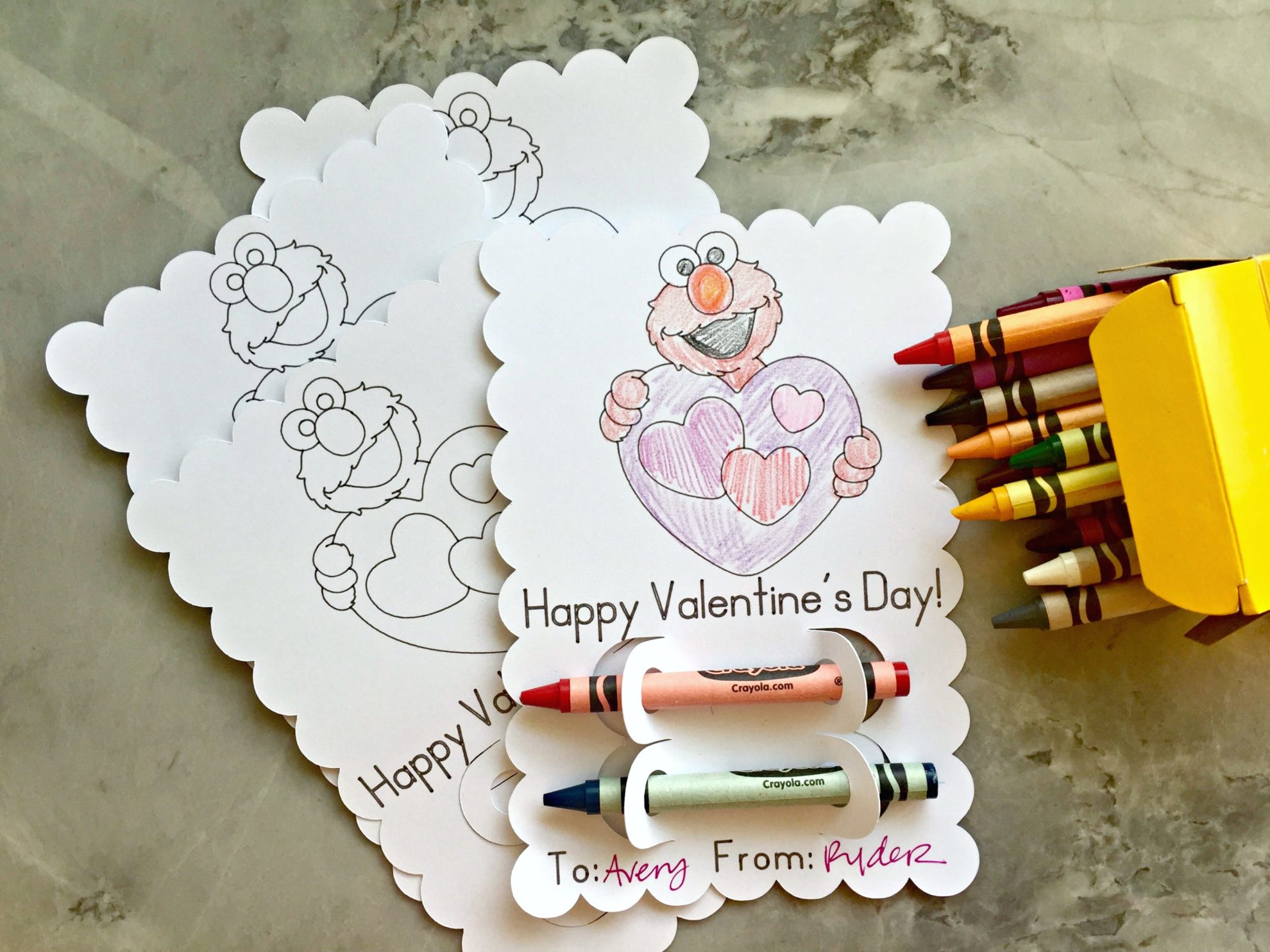 Top view of multiple colored elmo valentines with crayons.