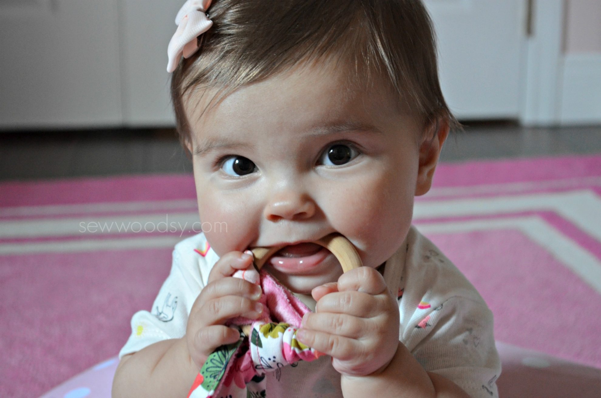 Teething ring with fabric with baby girl holding it.