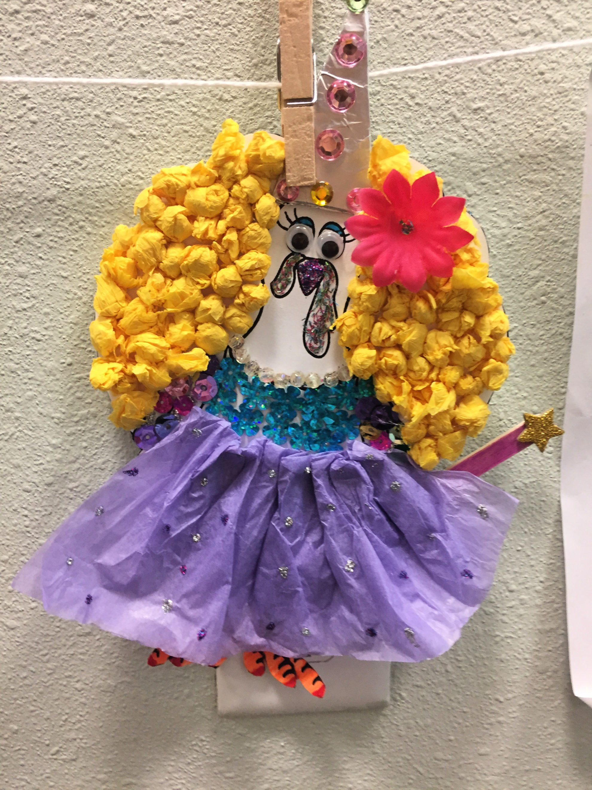 Cut Out Turkey In Disguise as a Fairy Godmother with little rolled tissue paper hair, pink flower, purple tissue paper skirt, and gems for a top.