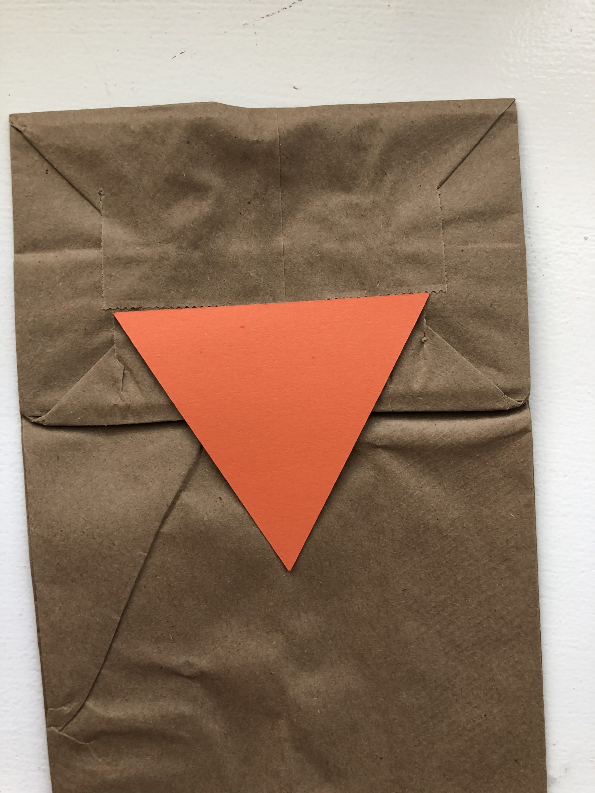 Top view of a brown paper bag with an orange triangle glued on the bag.