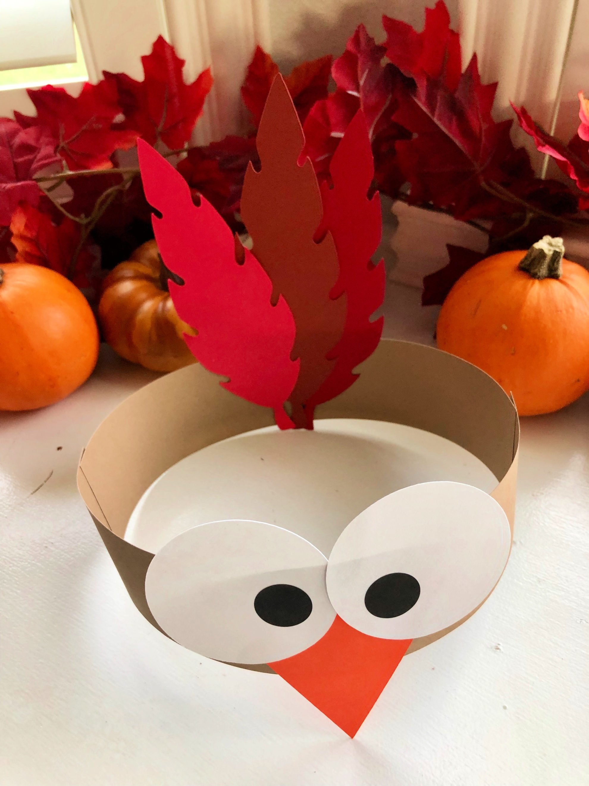 Top view of a turkey paper headband with fall leaves in the background.