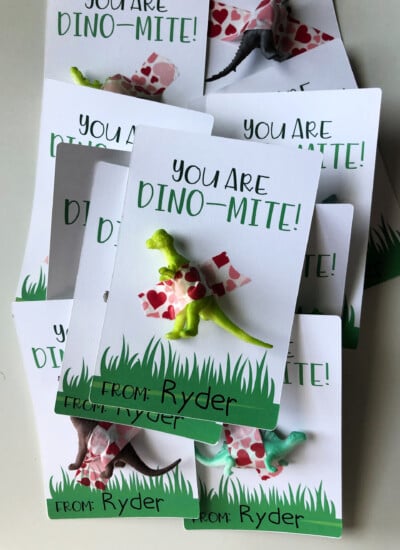 a pile of dinosaur valentines with dinosaurs taped to paper.