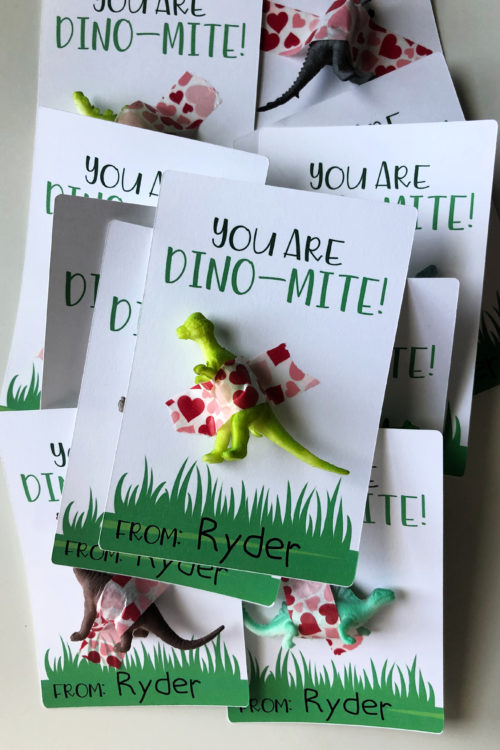 a pile of dinosaur valentines with dinosaurs taped to paper.