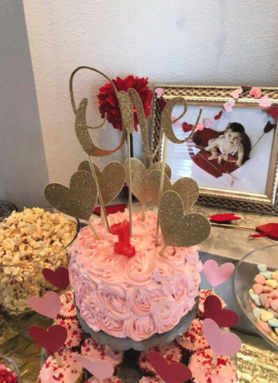 Close up of pink birthday cake with rose frosting and gold hearts