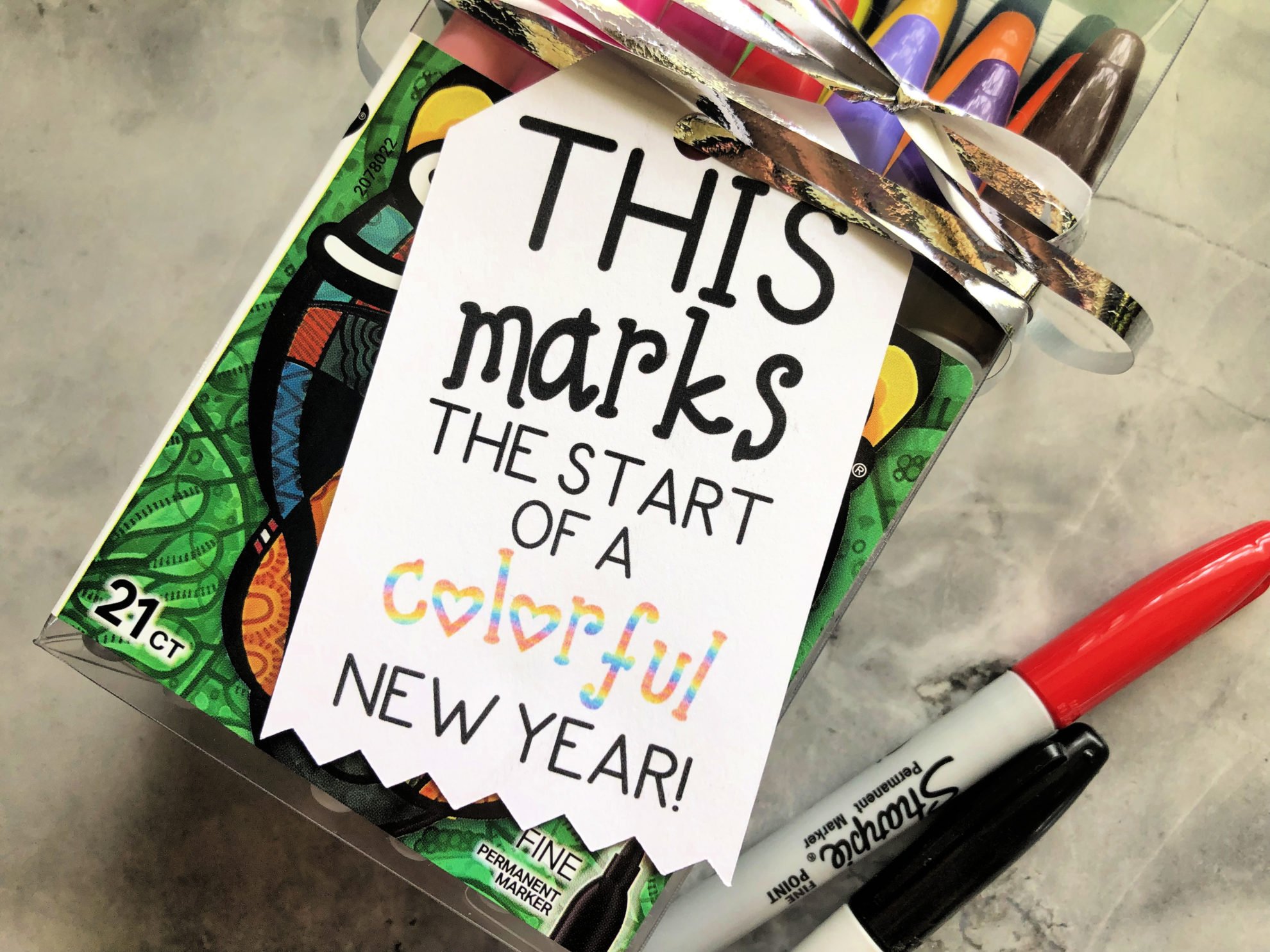 Close up of a tag that reads "this marks the start..." on a marble countertop with sharpies.