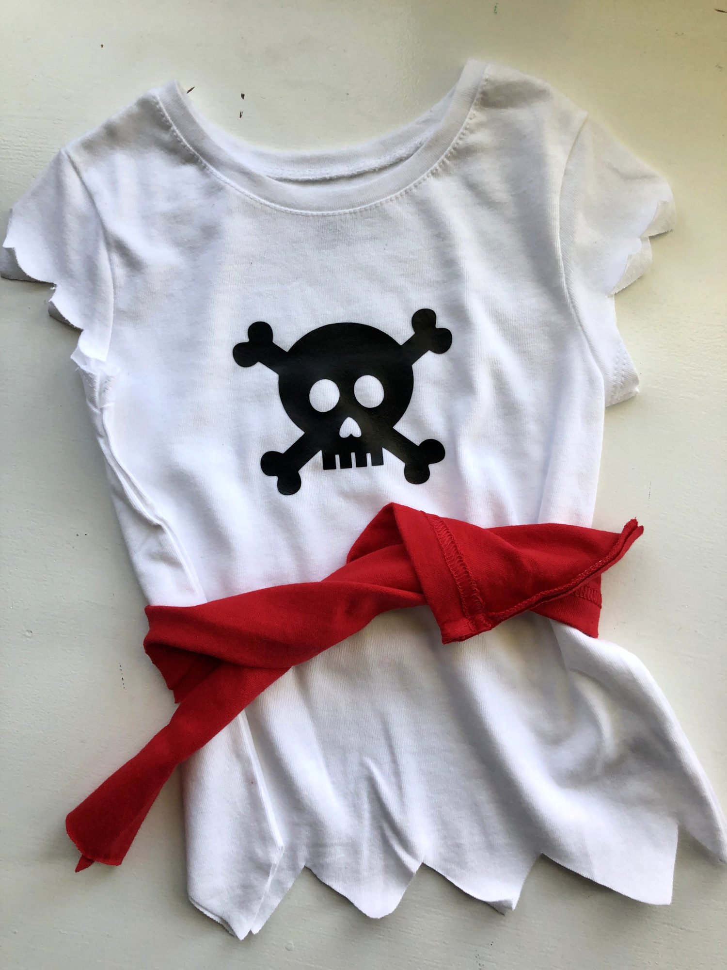 white shirt with black pirate skull and red belt. 