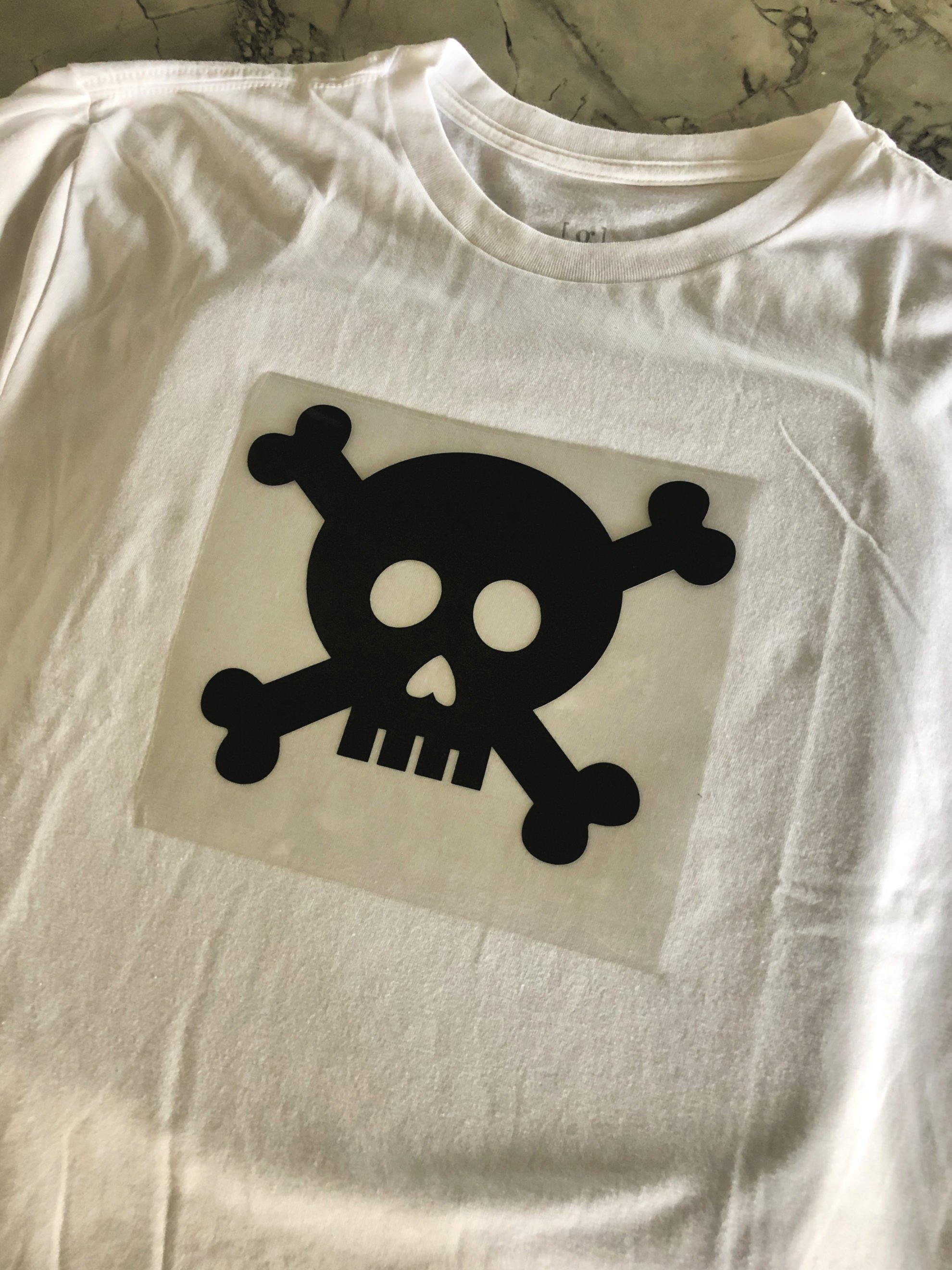 White tshirt with a skull and crossbones on the shirt.