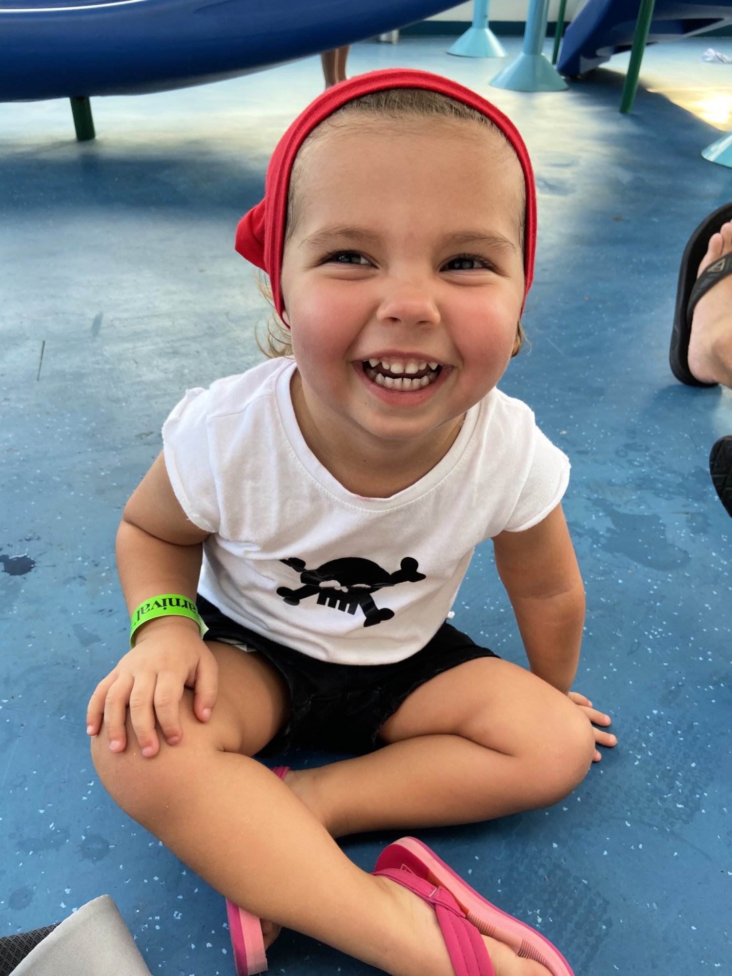 Toddler dressed in a pirate outfit sitting on a blue and white speckled floor. 