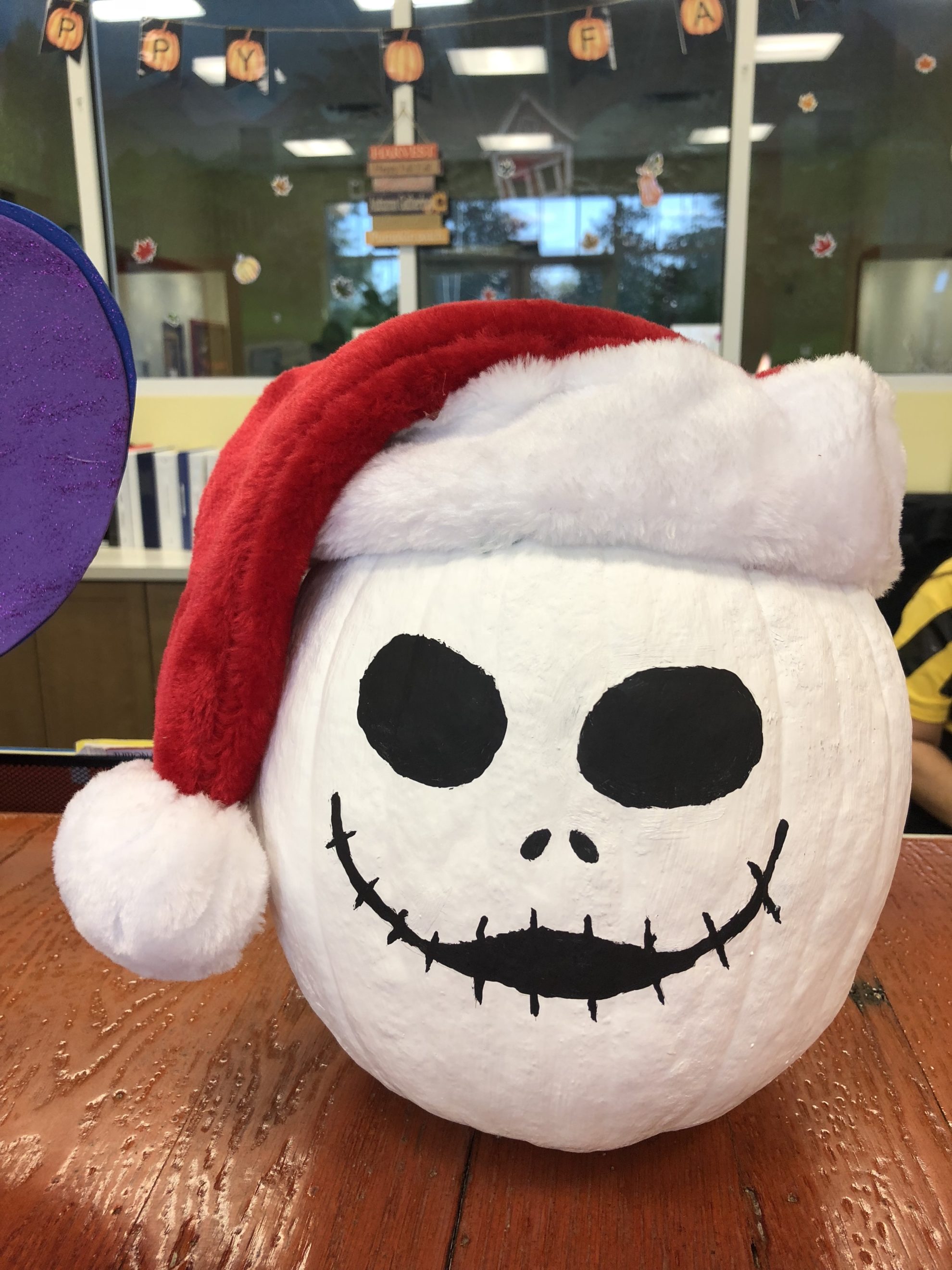 Jack Skellington white painted pumpkin with a red santa hat.