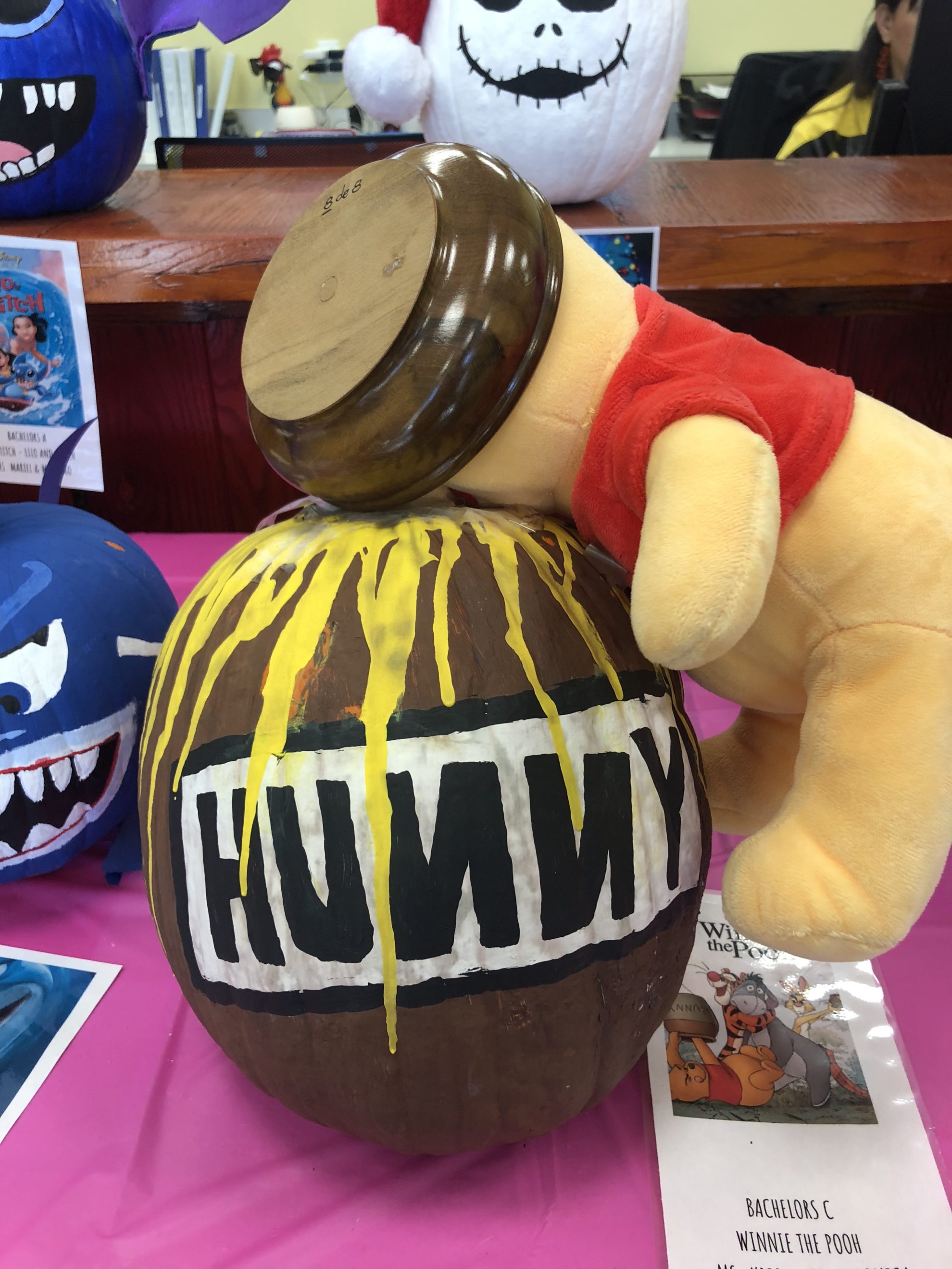 Winnie the Pooh stuffed animal sticking his head in a painted brown honey pot. 