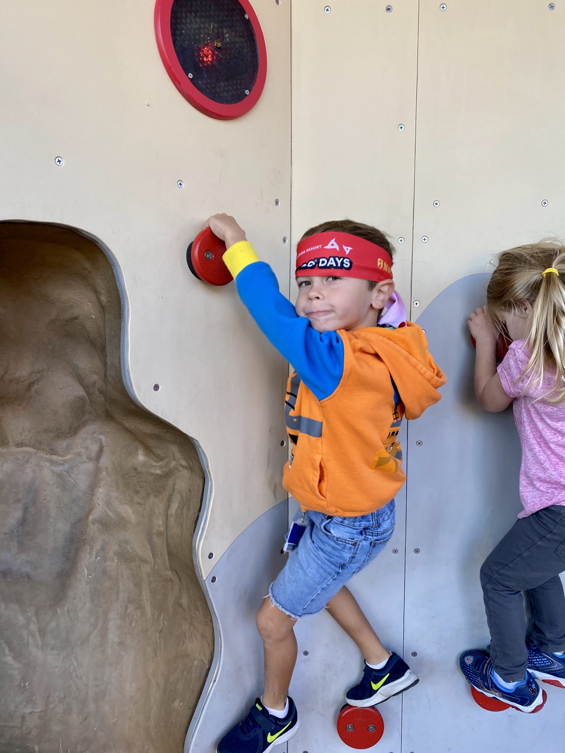 Little boy with red headband climbing in Ninjago land