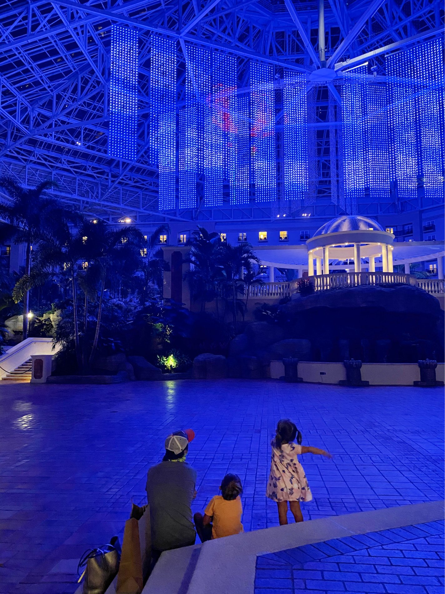 Father and children sitting on steps watching light show in a hotel. 