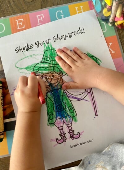 Child's hand colring a st. patrick's day coloring sheet.