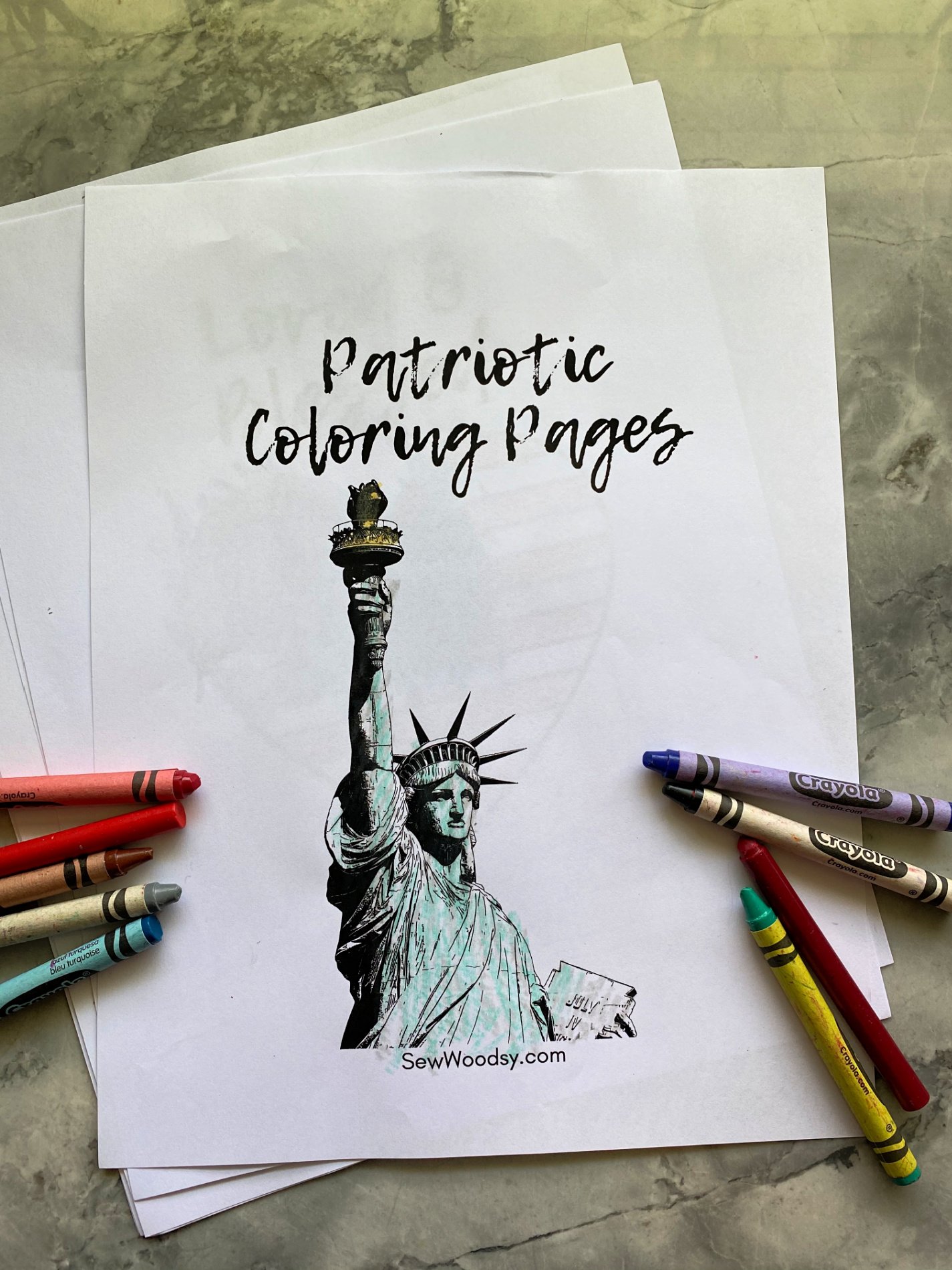 White coloring pages on marble countertop. Top coloring page of statue of liberty with crayons surrounding it.