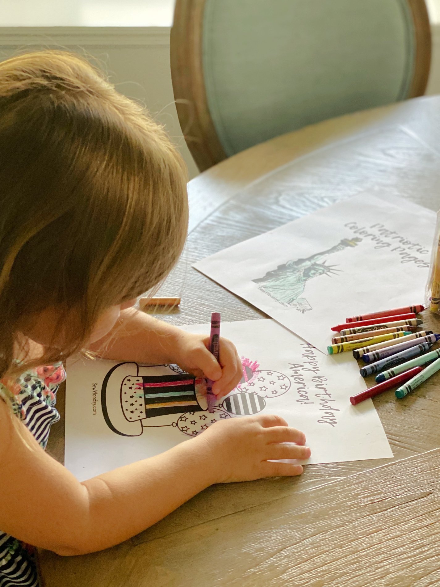 Little girl coloring at a wood table with crayons. 