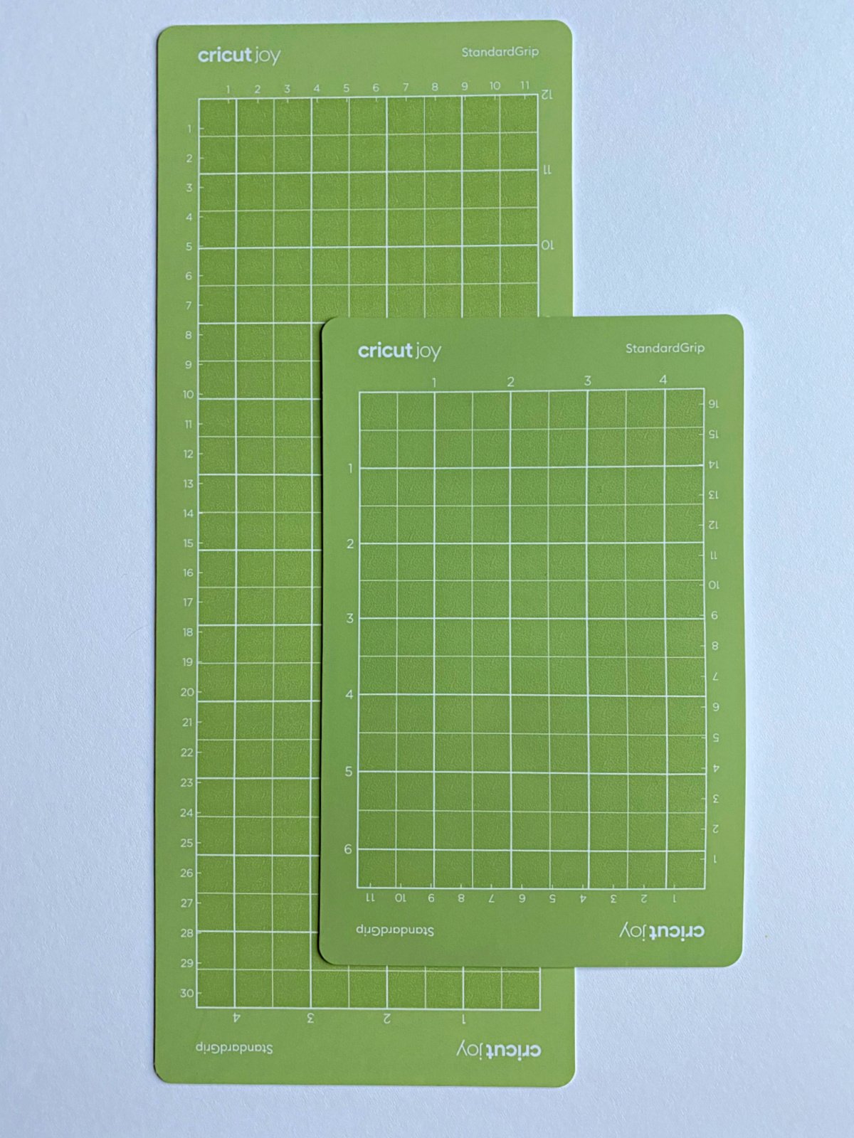Two Cricut Joy StandardGrip bright green mats on a white surface.