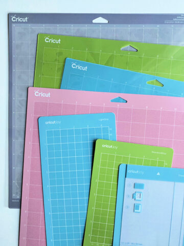 7 Cricut mats of various sizes layered on a white table.