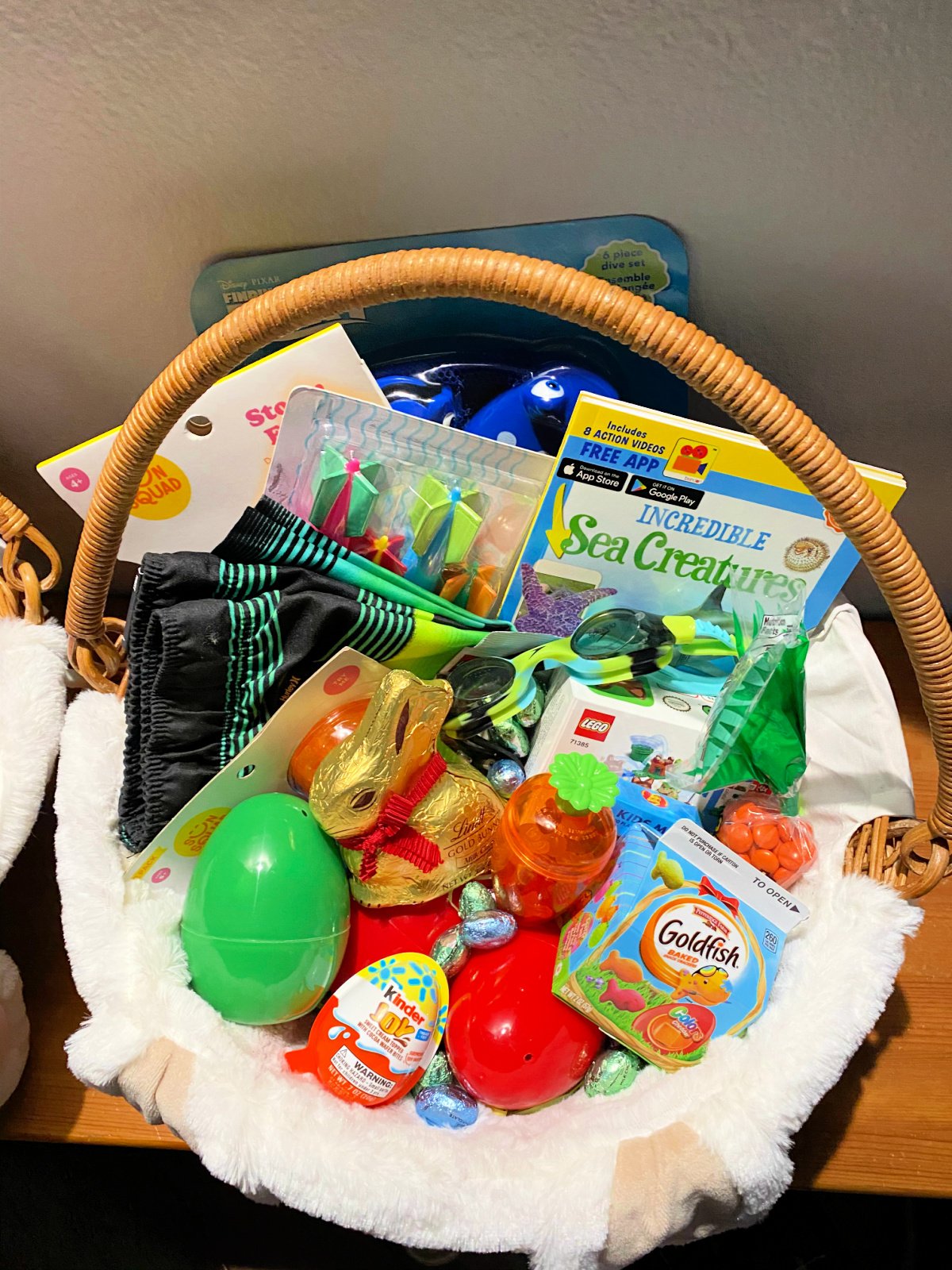 Easter basket with plastic eggs, candy, snacks, clothing, books, and water toys.