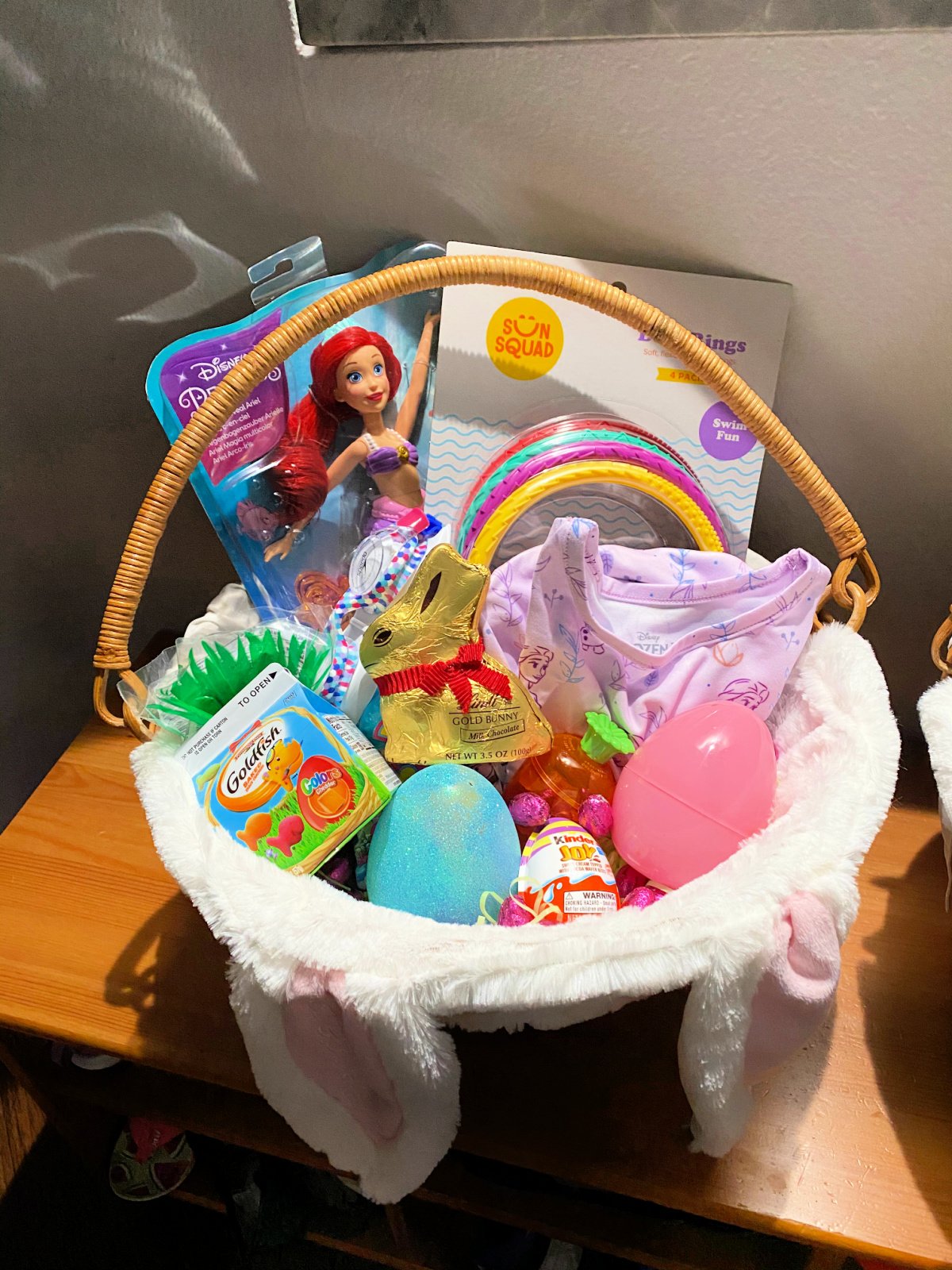 Easter basket filled with a mermaid barbie, plastic eggs, swim rings, and candy.