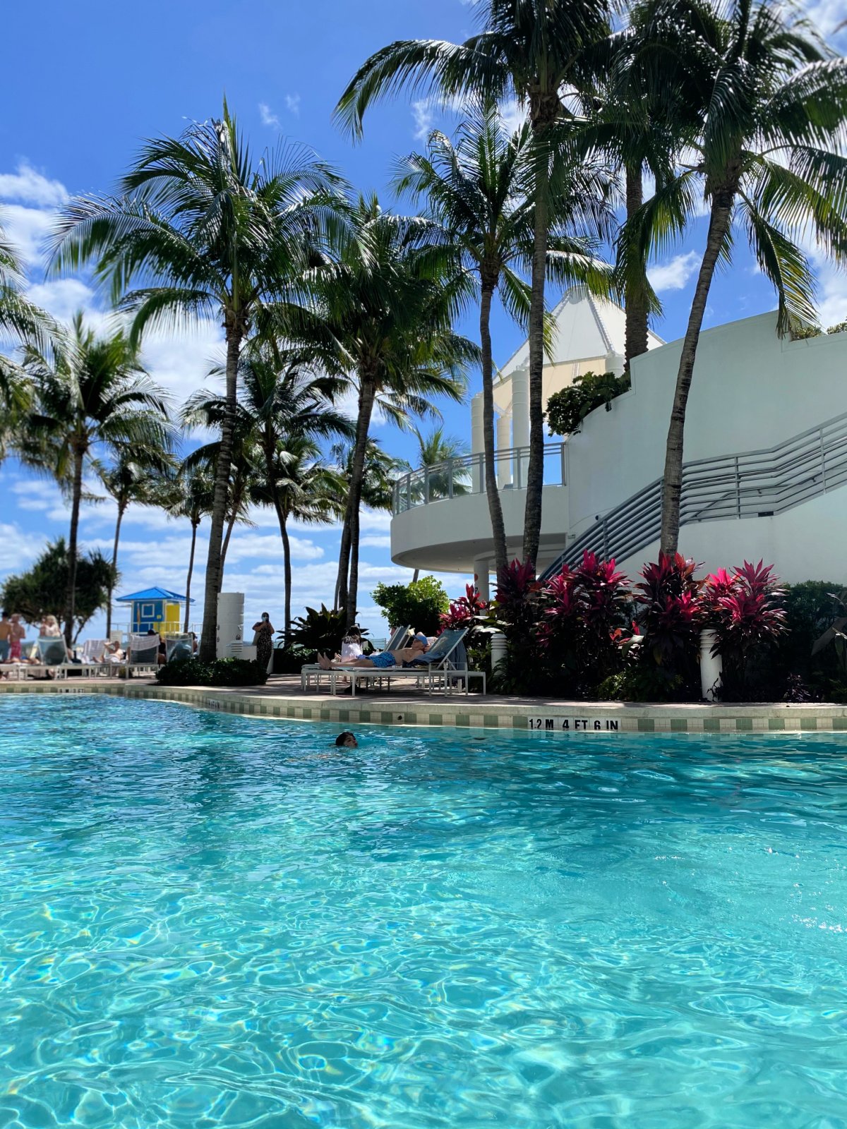 Bright blue pool with child swimming in it. 