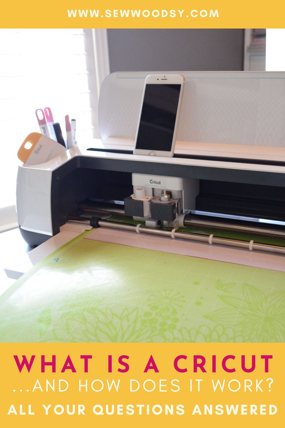 White Cricut machine with a green mat and iphone resting on top with text on the bottom of image.