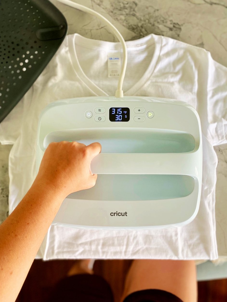 Hand holding a light blue EasyPress on top of a white shirt.