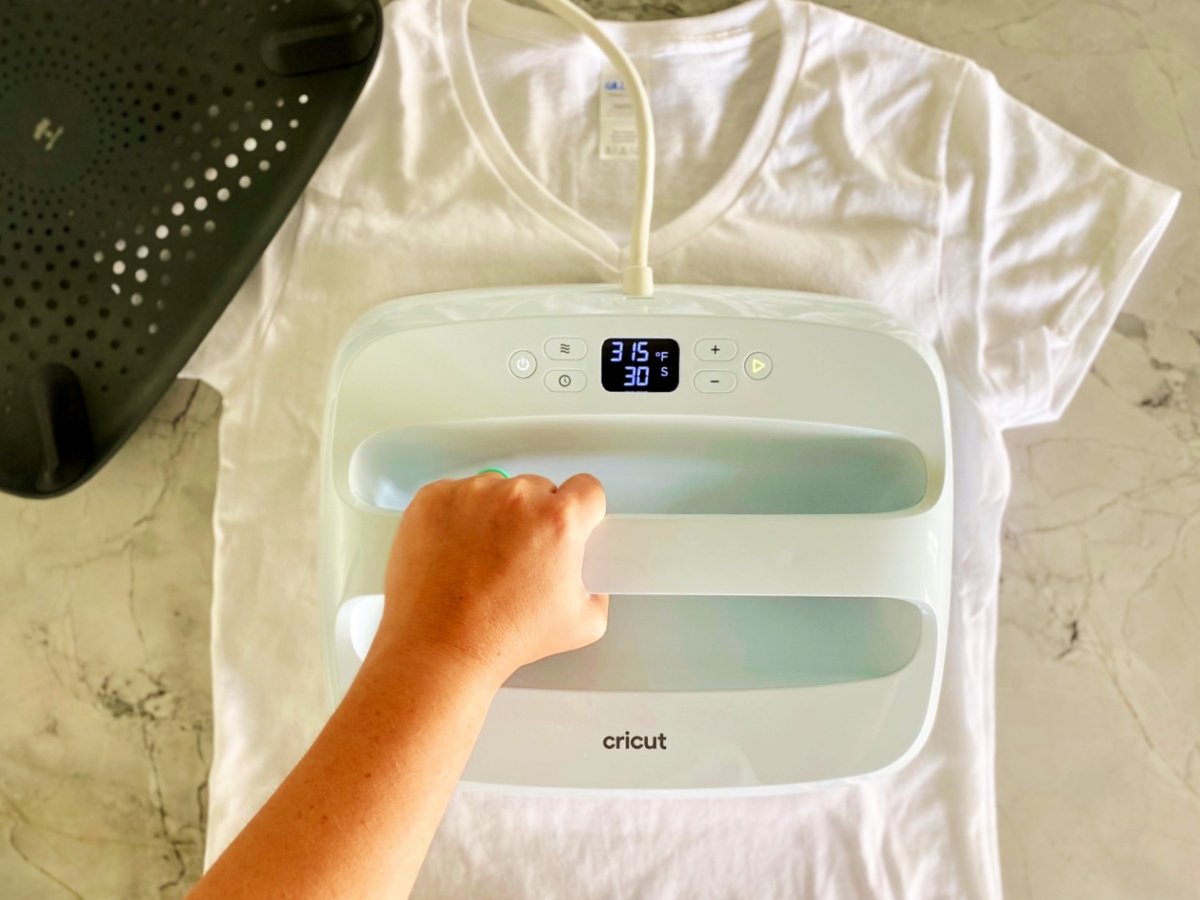 Handing pressing down a light blue EasyPress on a white shirt.