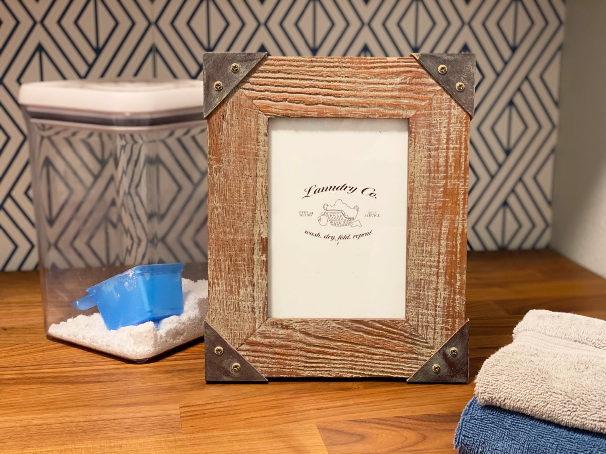 Wooden picture frame with a clear container with detergent next to it.