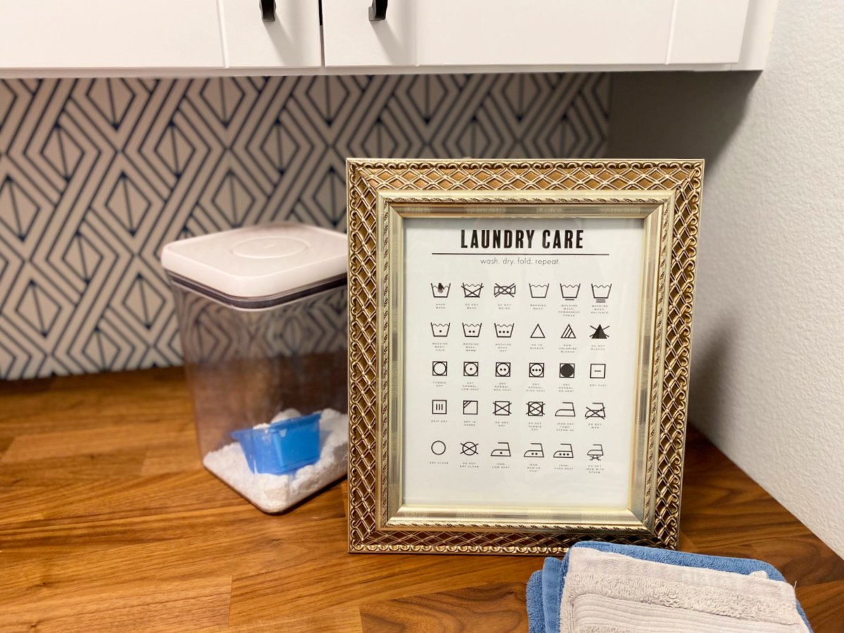 Gold frame with a sign called "laundry care" on a wood countertop.