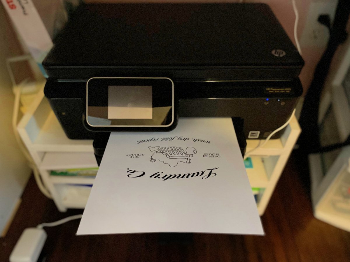 Black printer with a piece of paper that says "Laundry Co." on the printer.