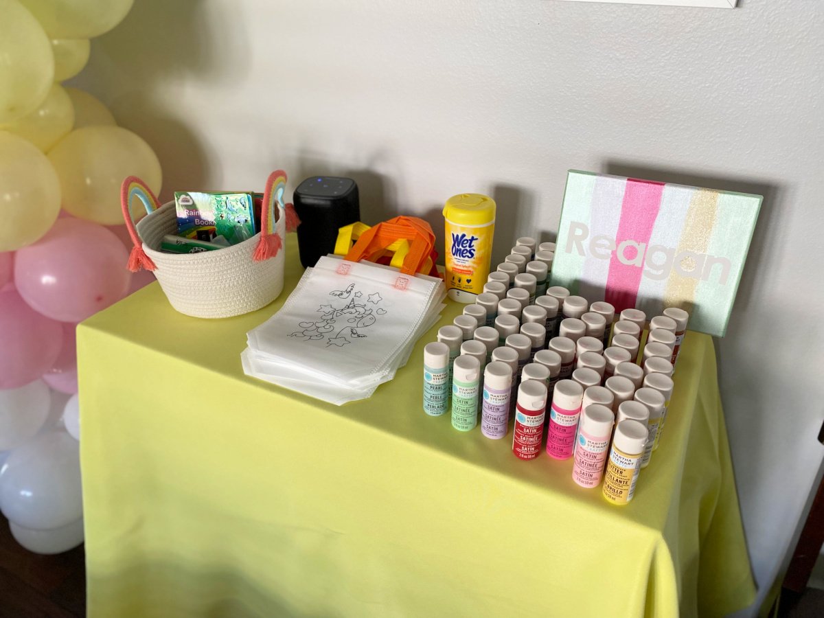 Yellow table cloth with paints, canvas, and coloring bags.