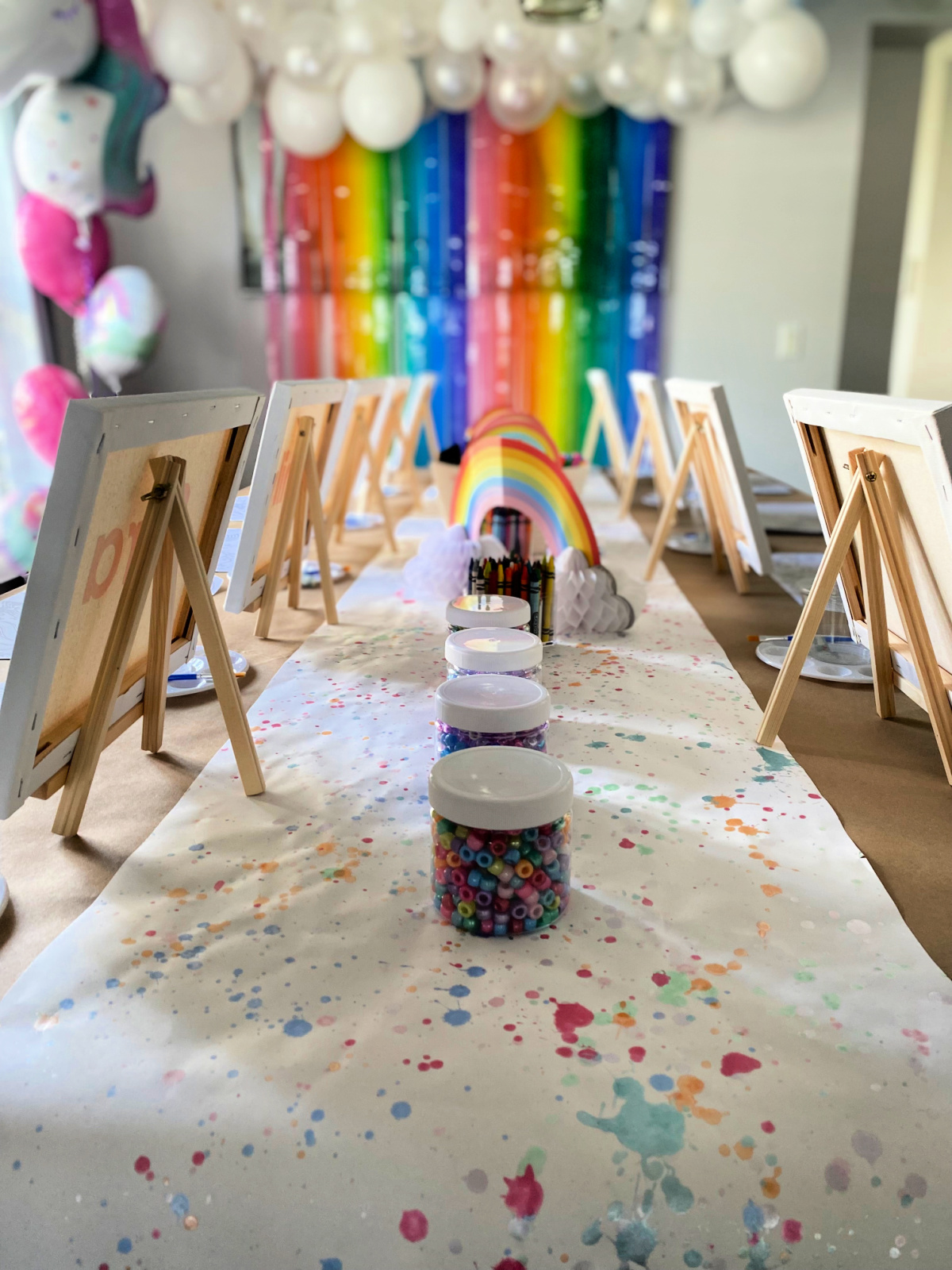 Four bead jars in the middle with easels and canvas on them.