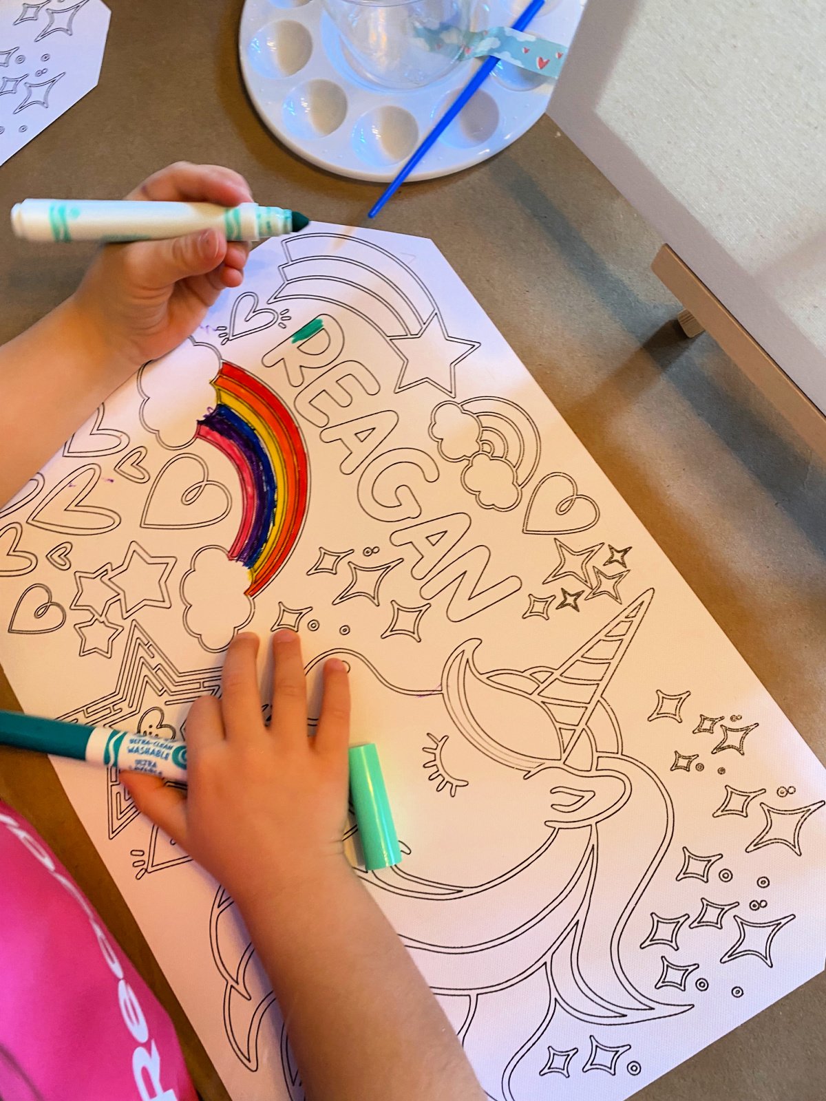 Little girl coloring her name with a green marker.