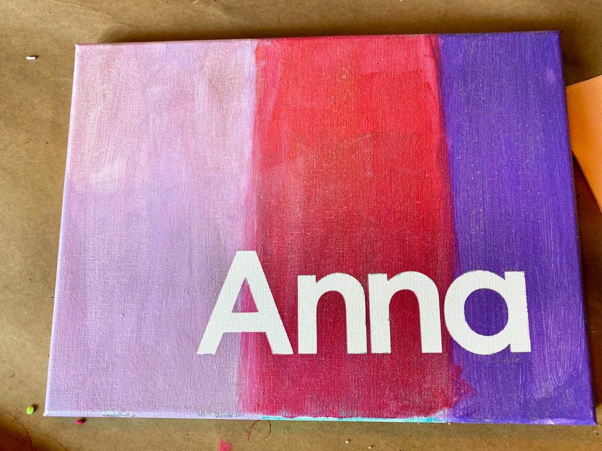 Light purple, pink, and dark purple painted canvas with the name "Anna" on it.