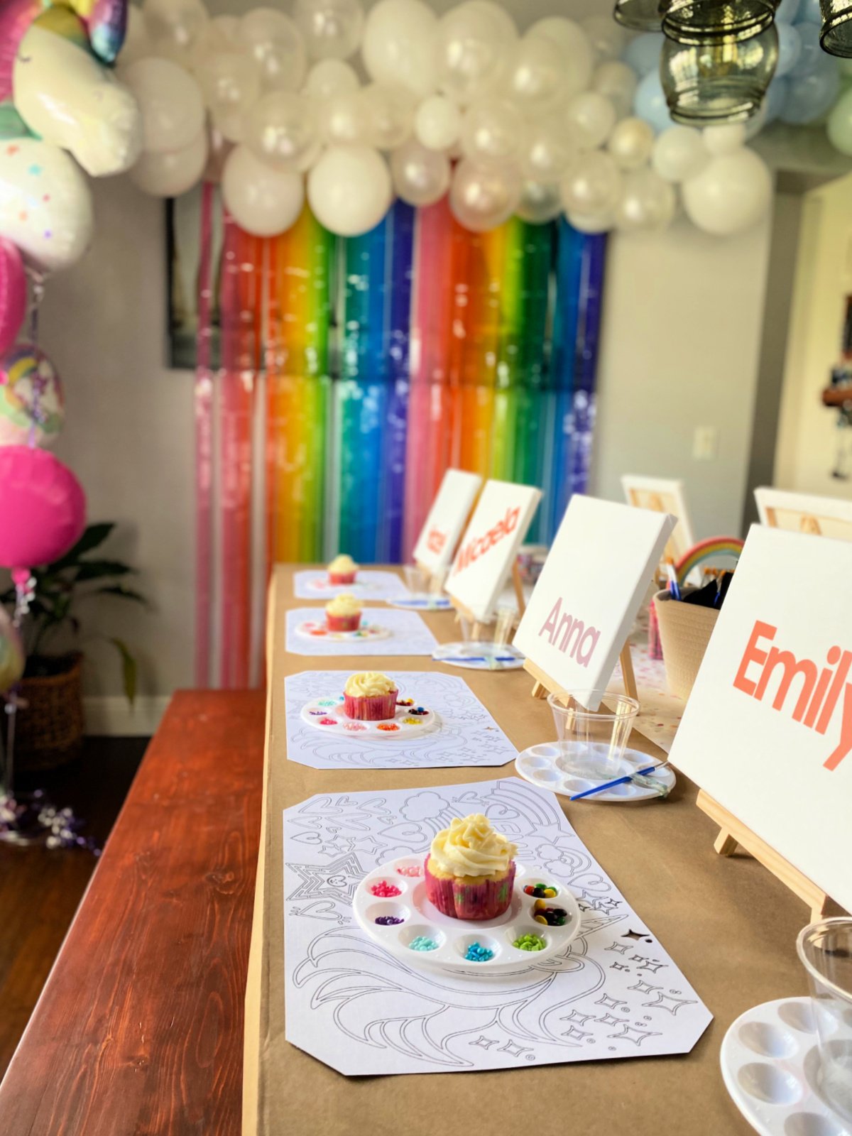 cupcakes on a table with a rainbow backdrop.