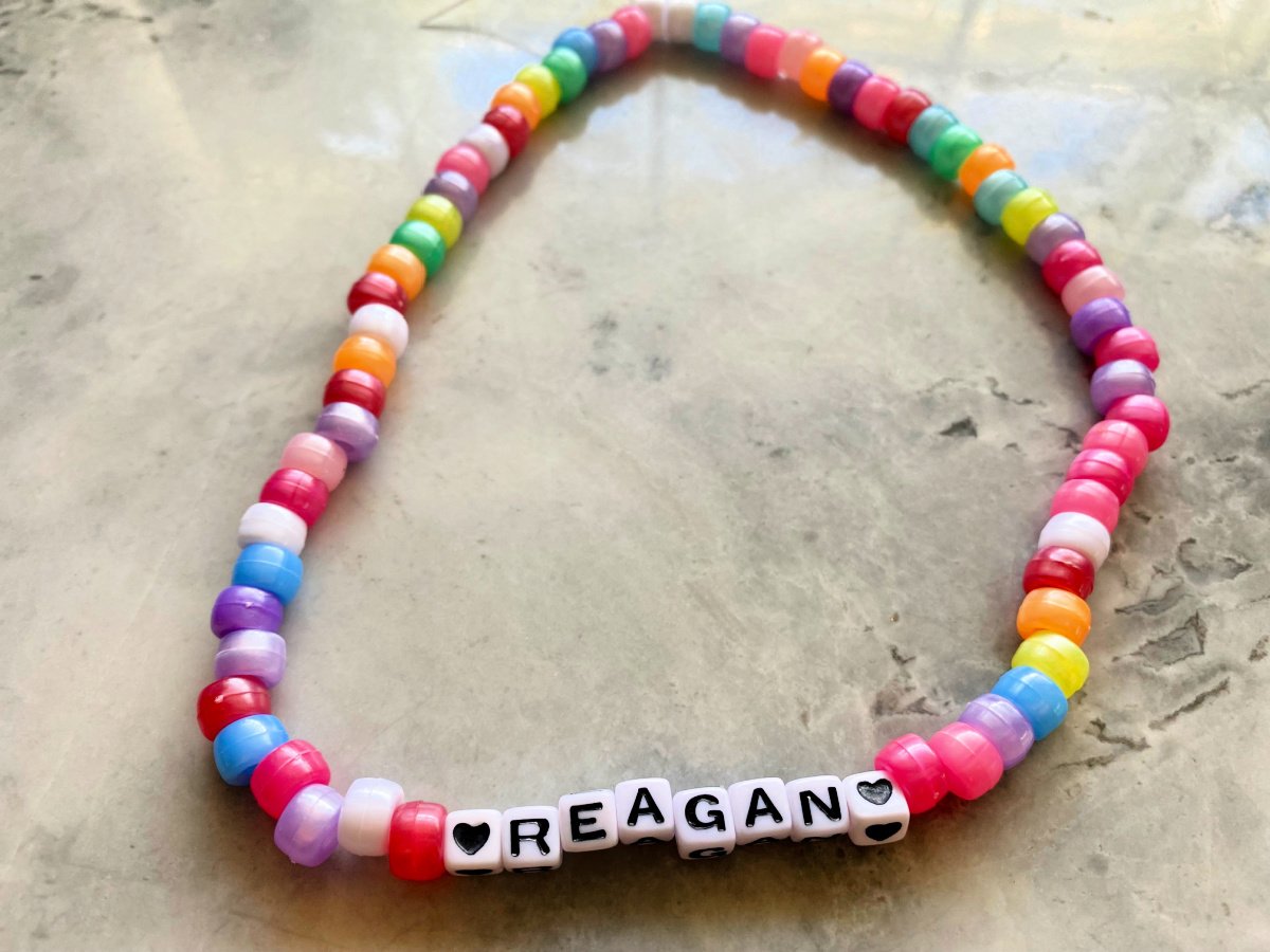 Beaded multi-color necklace with two hearts and the name "reagan".