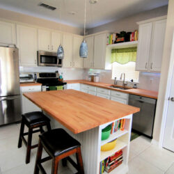 White kitchen with light wood butcher block countertops.